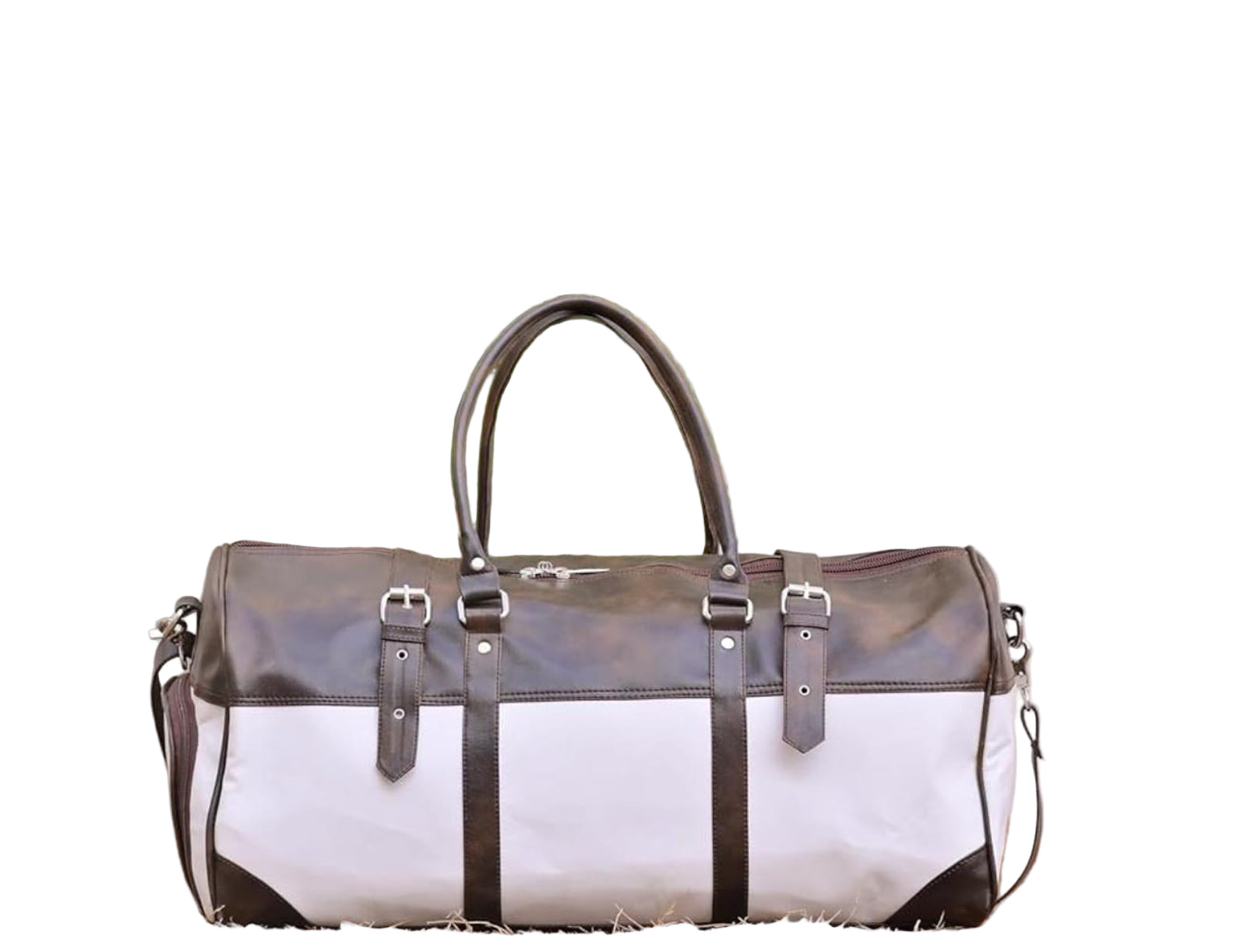 White and black leather duffel bag with brown accents against a neutral background