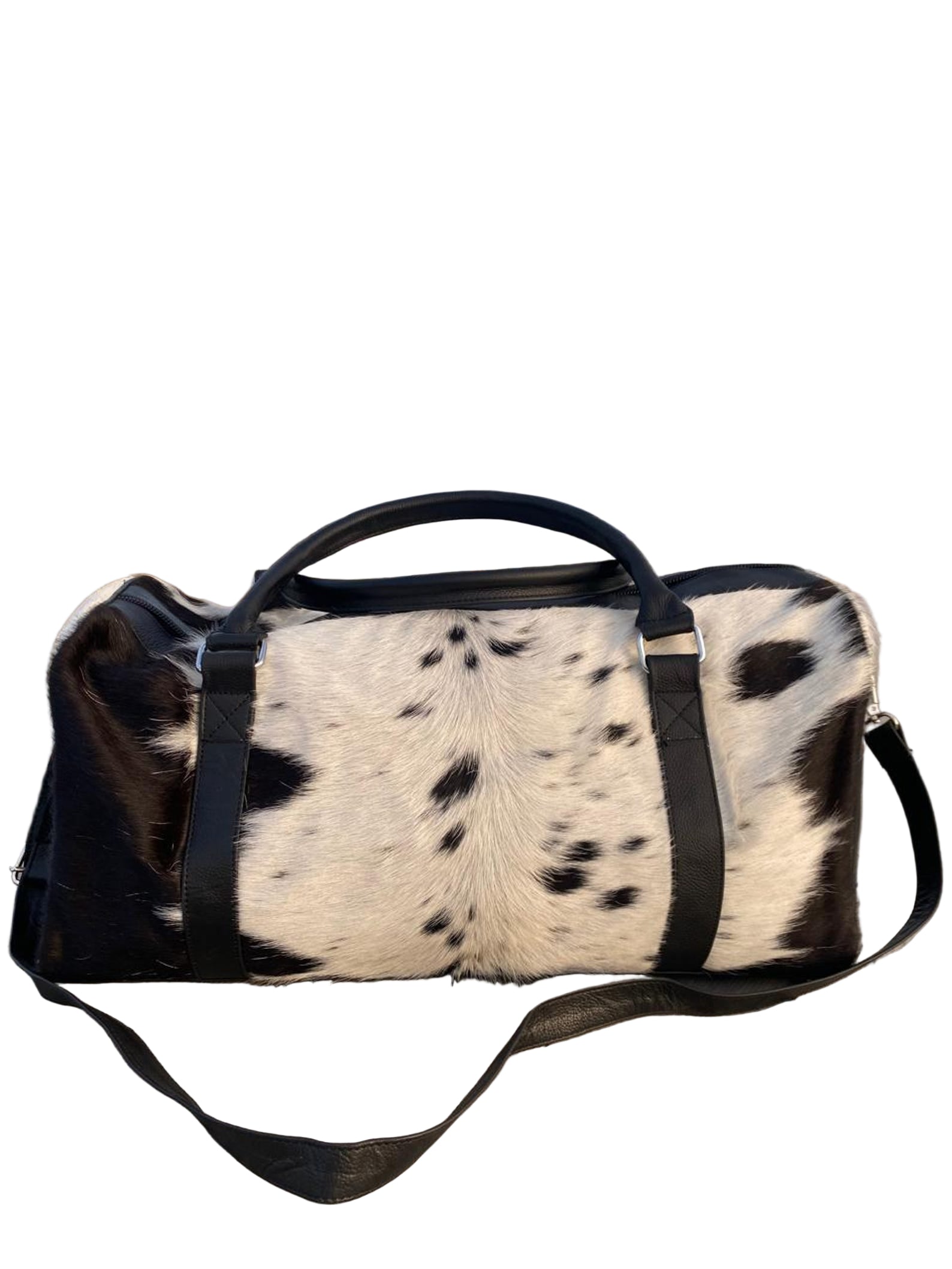 Duffle bag with cowhide pattern on a wooden surface with a beach in the background